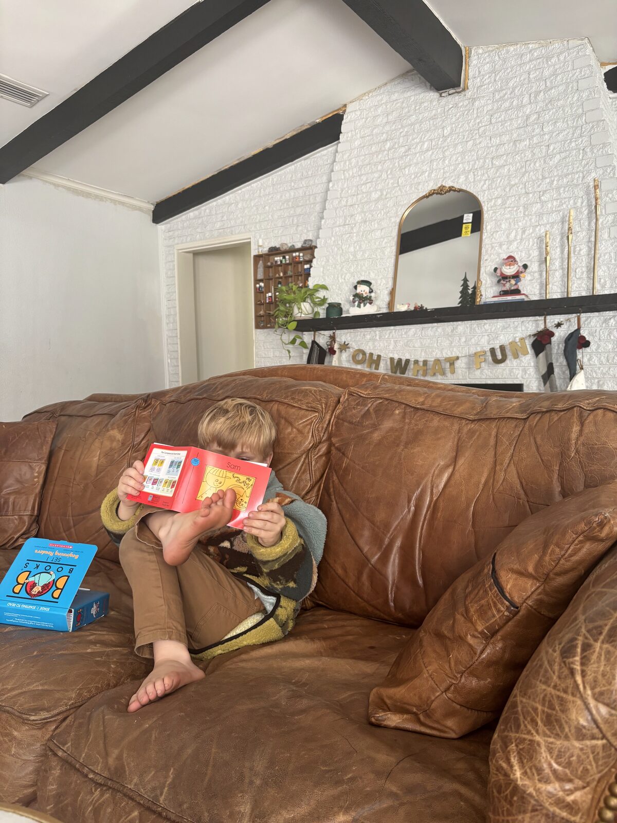 A child curled up on the couch at home, reading a book